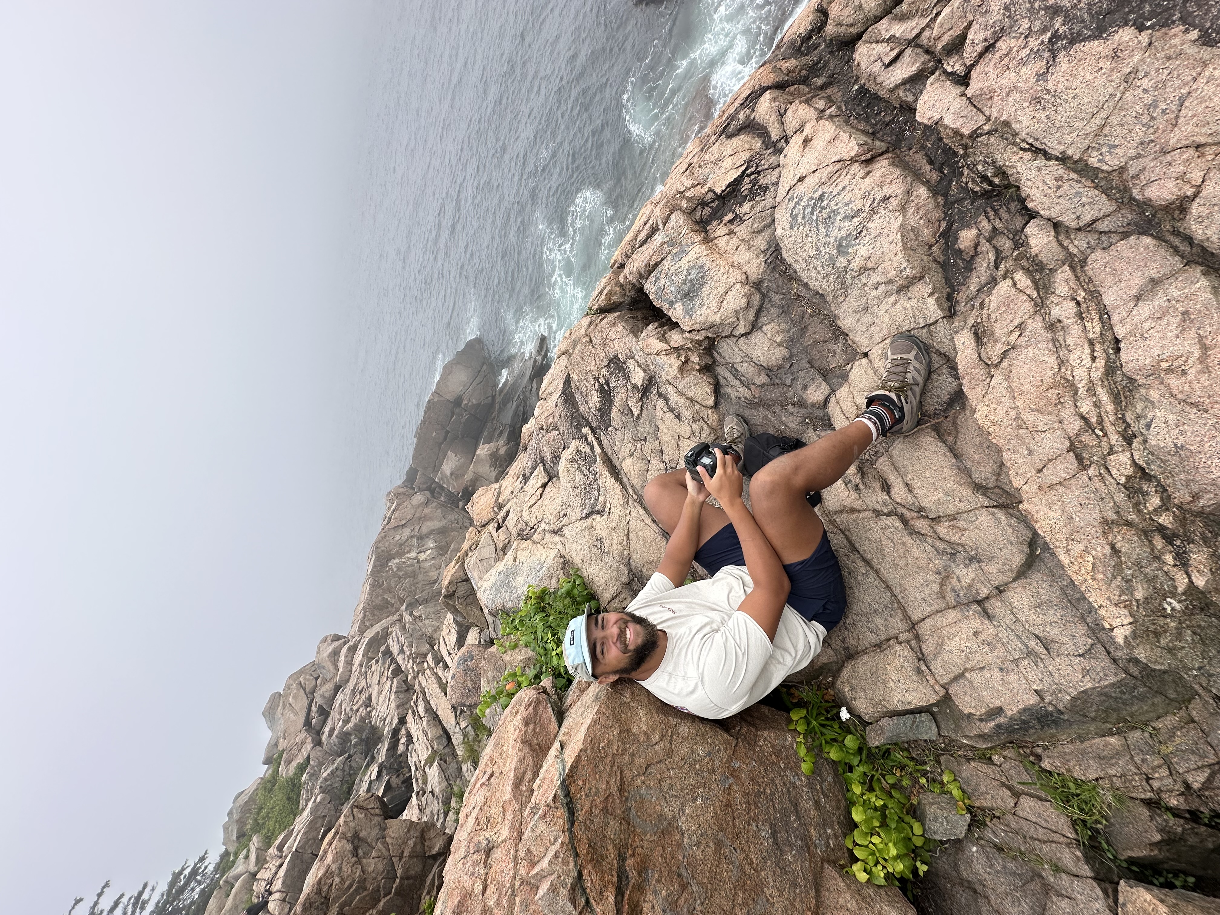 Cole sitting on coastal rocks